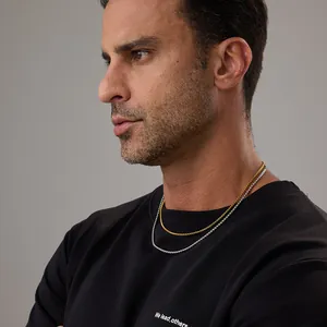 Colliers à chaînes superposées en or et argent portés sur un sweat-shirt noir