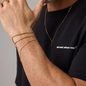 Dettaglio del set bracciale a serpente e collana dorati indossati su maglia nera