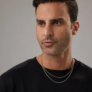 Gros plan de colliers à mailles dorées et argentées superposés sur un t-shirt noir