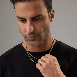Gros plan de colliers superposés en or et argent avec une bague minimaliste sur un mannequin