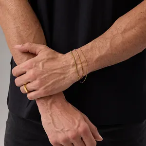 Dettaglio del bracciale a serpente dorato regolabile e anello a sigillo rettangolare
