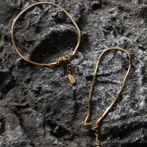 Dettaglio di bracciali a maglia serpente dorata con chiusura a moschettone su roccia