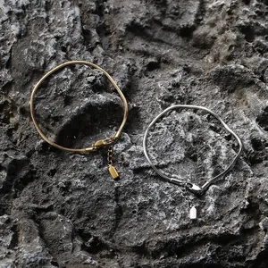 Dettaglio di bracciali a catena serpente regolabili in oro e argento con chiusure