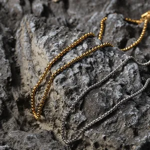 Détail des colliers à chaîne vénitienne dorée et argentée sur une roche texturée