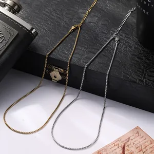 Détail de chaînes box dorées et argentées avec fermoirs mousqueton sur fond sombre texturé