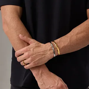 Detail of minimalist gold and silver beveled edge cuff bracelets and matching ring