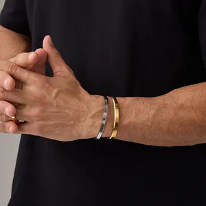 Close-up of minimalist gold and silver titanium steel open bracelets and ring for men