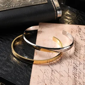 Close-up of minimalist gold and silver open cuff bracelets on vintage letter background