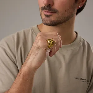 Dettaglio di un anello maschile a testa di lupo placcato oro con incisione 3D sulla mano