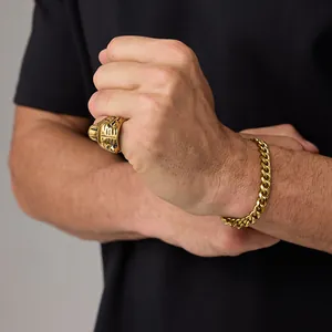 Detail shot of a men's gold tiger ring and cuban link bracelet on hand for a punk style