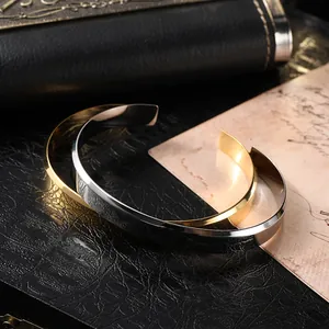 Detail of silver and gold cuff bracelets with mirror finish on black leather texture