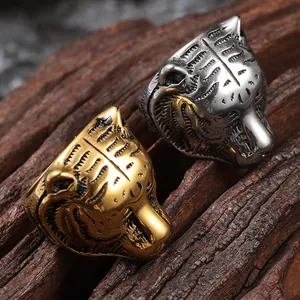 Detailed close-up of tiger head rings in silver and gold finish on wood