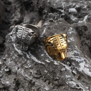 Macro detail of silver and gold stainless steel tiger head rings on dark stone