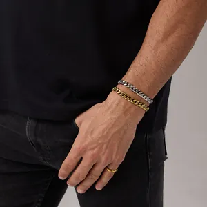 Dettaglio di bracciali a catena cubana oro e argento e un anello sul polso uomo