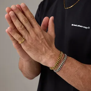 Dettaglio di bracciali a catena cubana oro e argento con anello d'oro lucido sulle mani