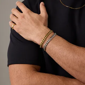 Dettaglio di bracciali a catena cubana oro e argento su polso maschile con anello