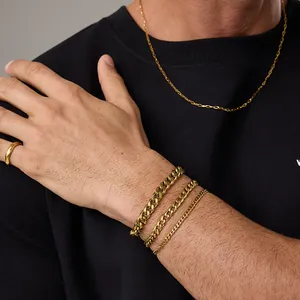 Primo piano di bracciali a catena cubana dorata a tre strati con finitura lucida al polso