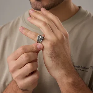 Detailed close-up of a vintage viking wolf head ring on a man finger with oxidized finish