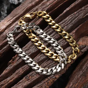 Dettaglio di bracciali a catena cubana oro e argento con chiusura a moschettone su legno