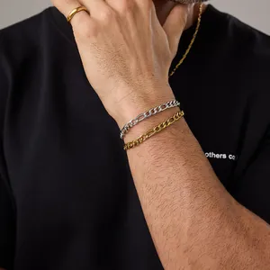 Détail de bracelets chaîne Figaro dorés et argentés avec bagues assorties sur mannequin