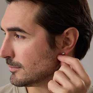 Close-up of a minimalist polished silver bead stud earring worn on a model's earlobe