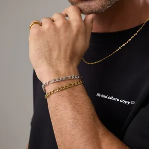 Détail de chaînes Figaro or et argent sur un mannequin au design industriel élégant
