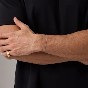 Close-up of a 18K gold ring with Cuban chain bracelets on a model wrist for daily wear