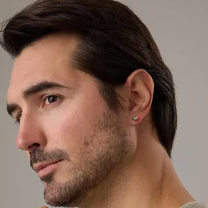 Close-up of a minimalist polished silver ball stud earring worn by a model