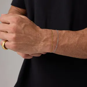 Close-up of minimalist 18K gold and silver thin Cuban chain bracelets with textured ring