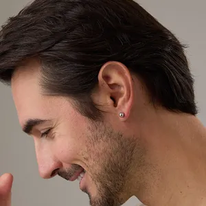 Close-up of a minimalist silver ball stud earring shown on an ear for size perspective
