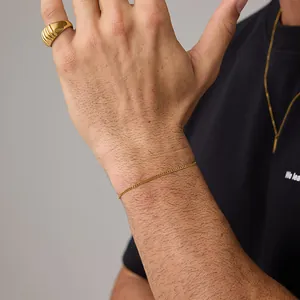 Close-up of minimalist 18K gold Cuban chain bracelet paired with a textured ring