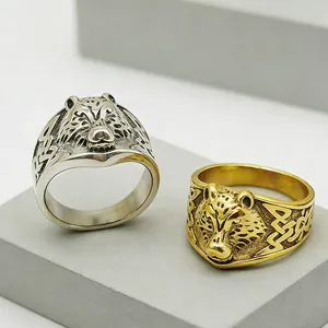 Close-up of vintage wolf head steel rings with Celtic knot textures on stone pedestal