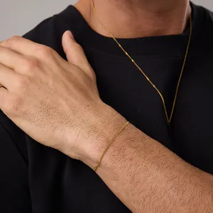 Close-up of sleek 18K gold-plated curb chain necklace and bracelet set on a model
