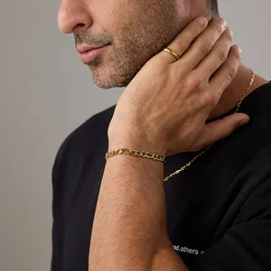 Bracelet chaîne Figaro dorée et bague lisse portés par un mannequin homme avec élégance