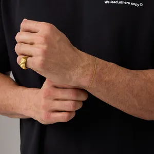 Close-up of 18K gold-plated slim Cuban chain bracelet and textured ring on wrist