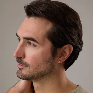 Close-up of a 4mm polished gold ball stud earring worn on a male model ear