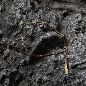 Detailed macro view of 18K gold thin Cuban chain bracelet on rock texture