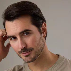 Minimalist gold ball stud earrings with high-polished metallic finish on male model