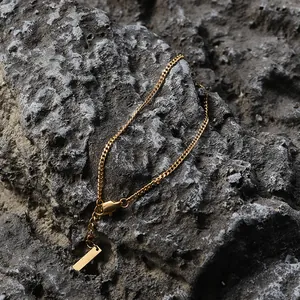 Detail shot of 18K gold Cuban link bracelet with lobster clasp on dark rock background