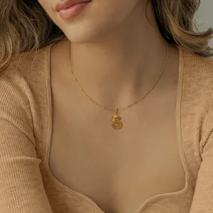 Gouden ketting met letter S hanger en satellietketting op een gebreide trui