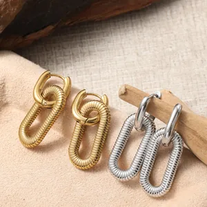 Boucles d'oreilles créoles torsadées or et argent sur support en daim et bois