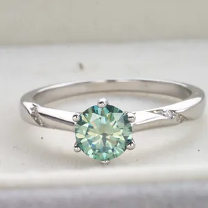 Macro shot of 1 carat teal moissanite ring with six-prong setting and side accents