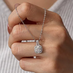 Macro detail of s925 silver halo pendant with round-cut moissanite held by a hand