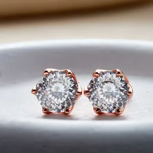 Vista macro di orecchini in oro rosa e moissanite con montatura a corona a sei griffe e diamanti