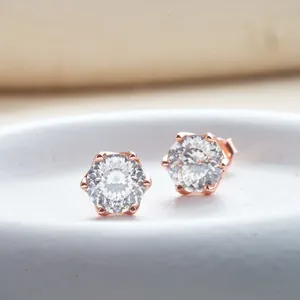 Primo piano di orecchini classici in oro rosa con zirconi rotondi e incastonatura a sei griffe