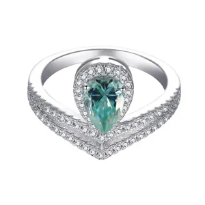 Macro shot of silver pear-shaped green gemstone ring with V-shaped halo diamond setting