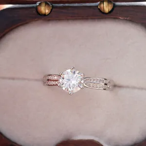 Detailed view of six-prong moissanite ring with paved side stones in luxury wood box
