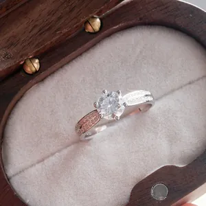 Detail of six-prong moissanite ring with two-tone band on velvet jewelry box