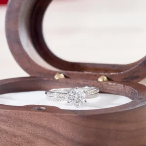 Macro view of six-prong moissanite ring with pavé side stones in a wooden jewelry box