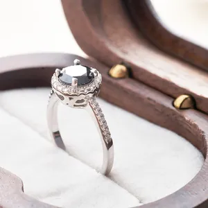Macro-opname van een zwarte moissaniet haloring op een luxe houten sieradendoosje